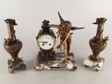 trois statues d'anges et une horloge posée sur une table
