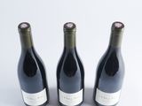 three bottles of wine are lined up on a white surface