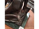 a bronze statue of a woman sitting on a green base