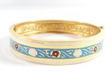 un gros plan d'un bracelet doré et bleu posé sur une surface blanche