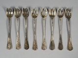 six silverware spoons and forks are lined up on a white surface