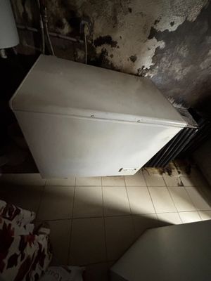 un réfrigérateur blanc dans un coin d'une pièce sale