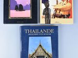 trois livres posés sur une table, avec une statue d'un homme devant un bâtiment