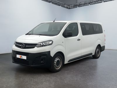 La camionnette blanche est garée dans une grande pièce blanche.