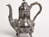 une théière ancienne en argent surmontée d'un oiseau