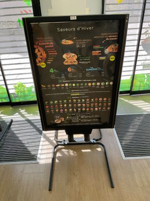 a menu board on a stand in front of a window