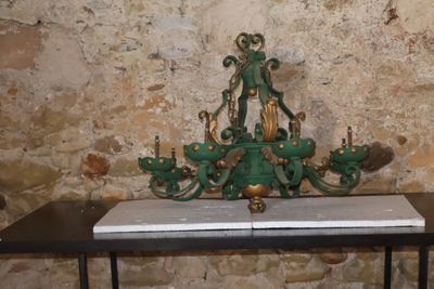 a green chandelier on a table in front of a stone wall