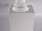 une sculpture blanche représentant un chien assis sur une boîte