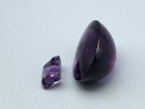 a purple stone and a purple diamond on a white surface