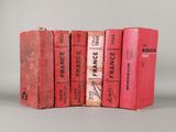 Plusieurs livres rouges sont empilés les uns sur les autres sur une table