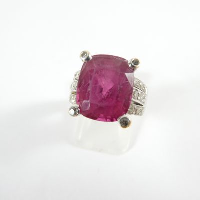 un gros plan d'une bague ornée d'une pierre rose sur un fond blanc
