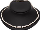 a white pearl necklace on a black mannequin with a gold clasp