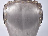 a silver vase with gold rivets on it