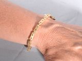 someone is wearing a gold bracelet with a chain on it