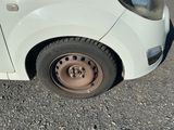 a small white car with a flat tire on the street
