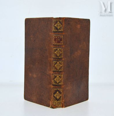 un vieux livre marron aux tranches dorées posé sur une table blanche