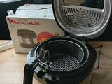an air fryer sitting on top of a wooden table next to a box of food