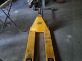 un chariot élévateur dans un garage, avec d'autres outils en arrière-plan
