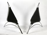 pair of black leather chairs with chrome legs on a white background