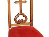 une chaise en bois avec une assise rouge et une croix sur le dossier