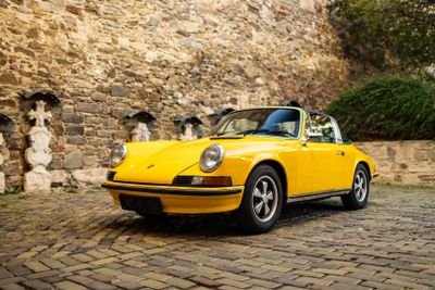 a yellow car parked in front of a stone wall