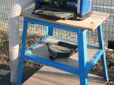 un chariot bleu sur lequel est posé un micro-ondes, à côté d'une clôture