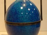 a blue vase with a metal handle sitting on a table