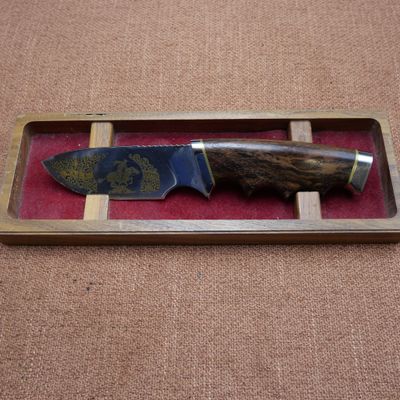 un couteau qui se trouve dans une boîte en bois posée par terre