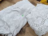 two pieces of white crocheted clothing on a table