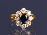 un gros plan d'une bague sertie d'un saphir bleu et de diamants, posée sur une surface réfléchissante