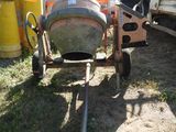 a cement mixer sitting in the grass next to a truck