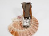 a watch sitting on top of a shell on a white surface