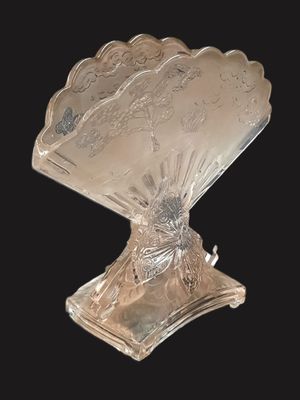 une assiette en argent ancien représentant un éventail posé sur un socle, sur fond noir