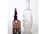 une bouteille en verre et une statue représentant une main, placées l'une à côté de l'autre
