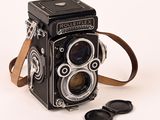 an old camera with a leather strap next to a pair of sunglasses
