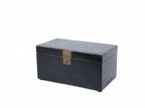 une petite boîte noire sur laquelle est accrochée une étiquette dorée