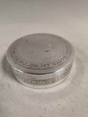 une boîte ancienne plaquée argent posée sur une surface blanche