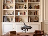 a table with a dolphin statue on it in front of bookshelves