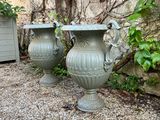 two green vases sitting on the gravel in the garden