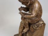 a statue of a child sitting on a stool