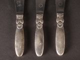 three silverware pieces with a design on them on a black surface