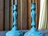 deux bougies bleues posées sur une table devant un rideau