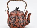 teapot decorated with birds and flowers on a brown background