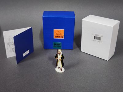 une petite figurine représentant un couple de jeunes mariés devant une boîte bleue