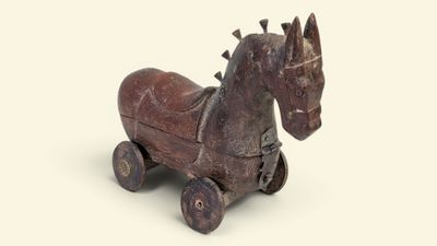 un cheval en bois qui est posé sur une surface blanche