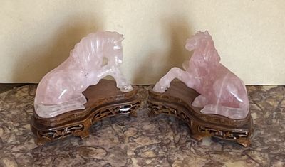 une paire de serre-livres en forme de chevaux en cristal rose posés sur une table en marbre