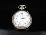 a silver pocket watch with a white face on a black surface