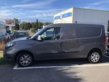 La camionnette grise est garée sur le parking à côté de l'immeuble.