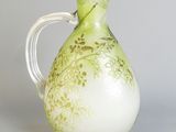 a green and white vase with a handle on a table