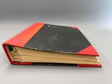 un livre rouge et noir posé sur une table blanche